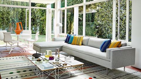 A bright, light living room with a Bolster sofa in white fabric next to a selection of Eames Wire Base Low Tables with white laminate set as coffee tables.