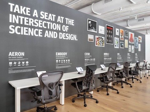 A row of gray office chairs including Aeron, Embody, Cosm, and Mirra 2, line the Performance Seating display in the Fulton Market Showroom. 