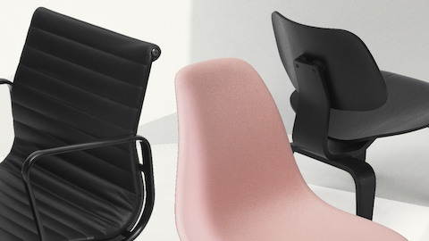 A black leather Eames Aluminum Group Chair, a pink Eames Shell Chair, and a black Eames Molded Plywood Chair grouped together.