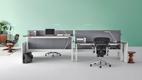 A Renew Link sit-to-stand benching system with gray divider screens and Aeron chairs. Select to go to our height-adjustable products page.