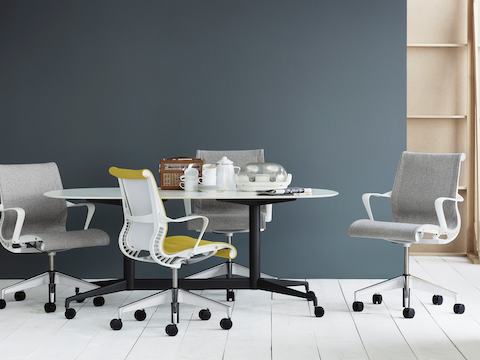 Light gray and yellow Setu office chairs around a Locale table with a white top and black base.