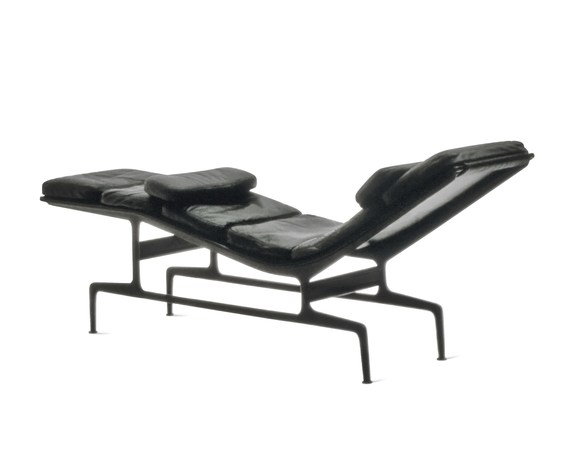 An all-black Eames Chaise, viewed from the back at an angle.