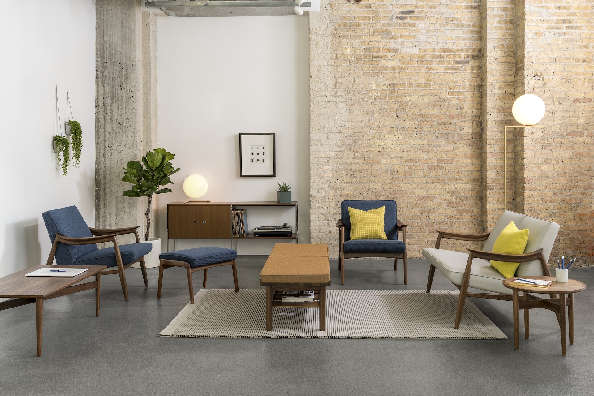 A casual lounge setting with Aspen Lounge Seating with walnut bases, a Tamarack Table and Bench in walnut, and Hemlock tables in walnut.