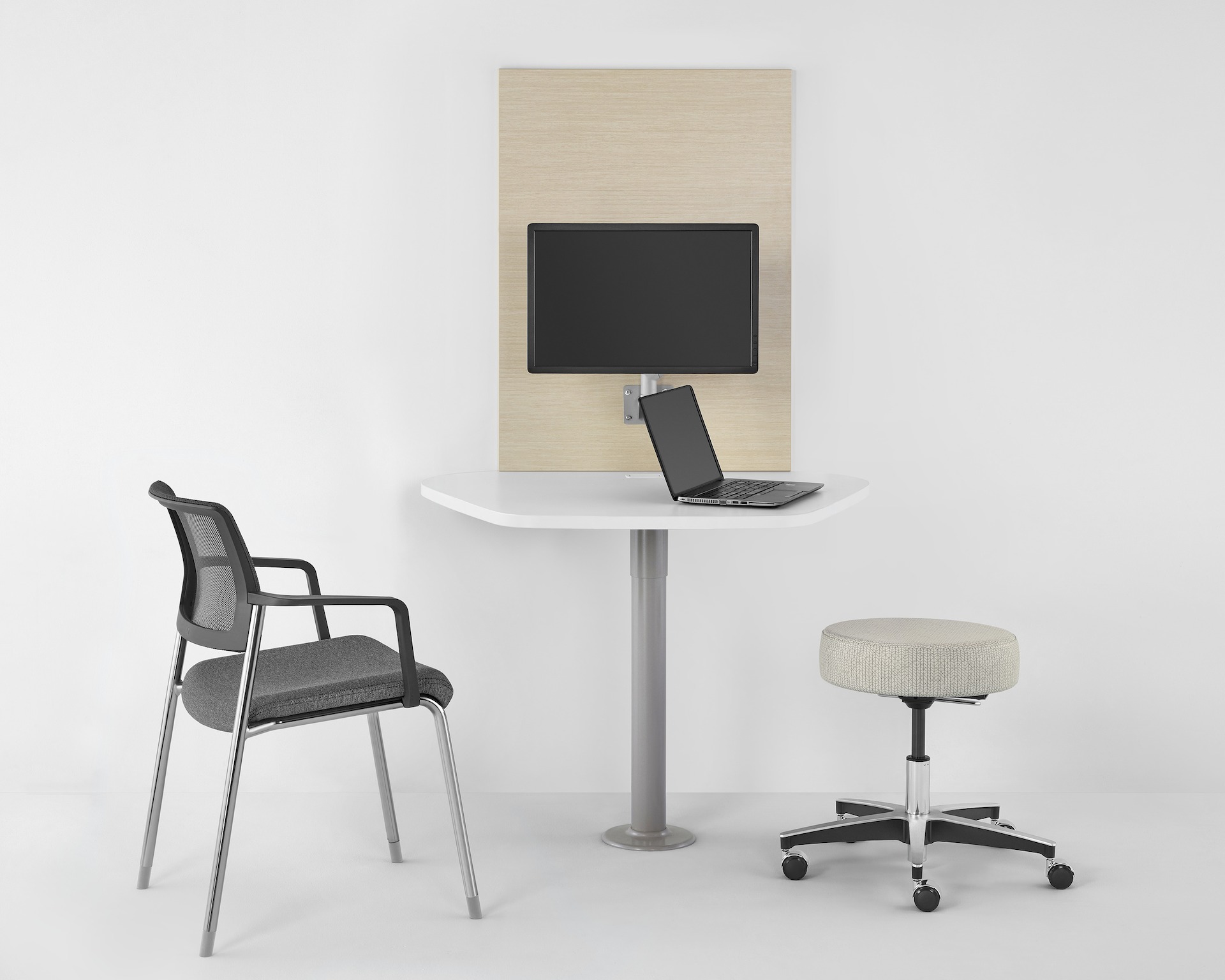 A patient room with light finish table using Mora System, one Versus Side Chair, and one Physician Stool in light textile.