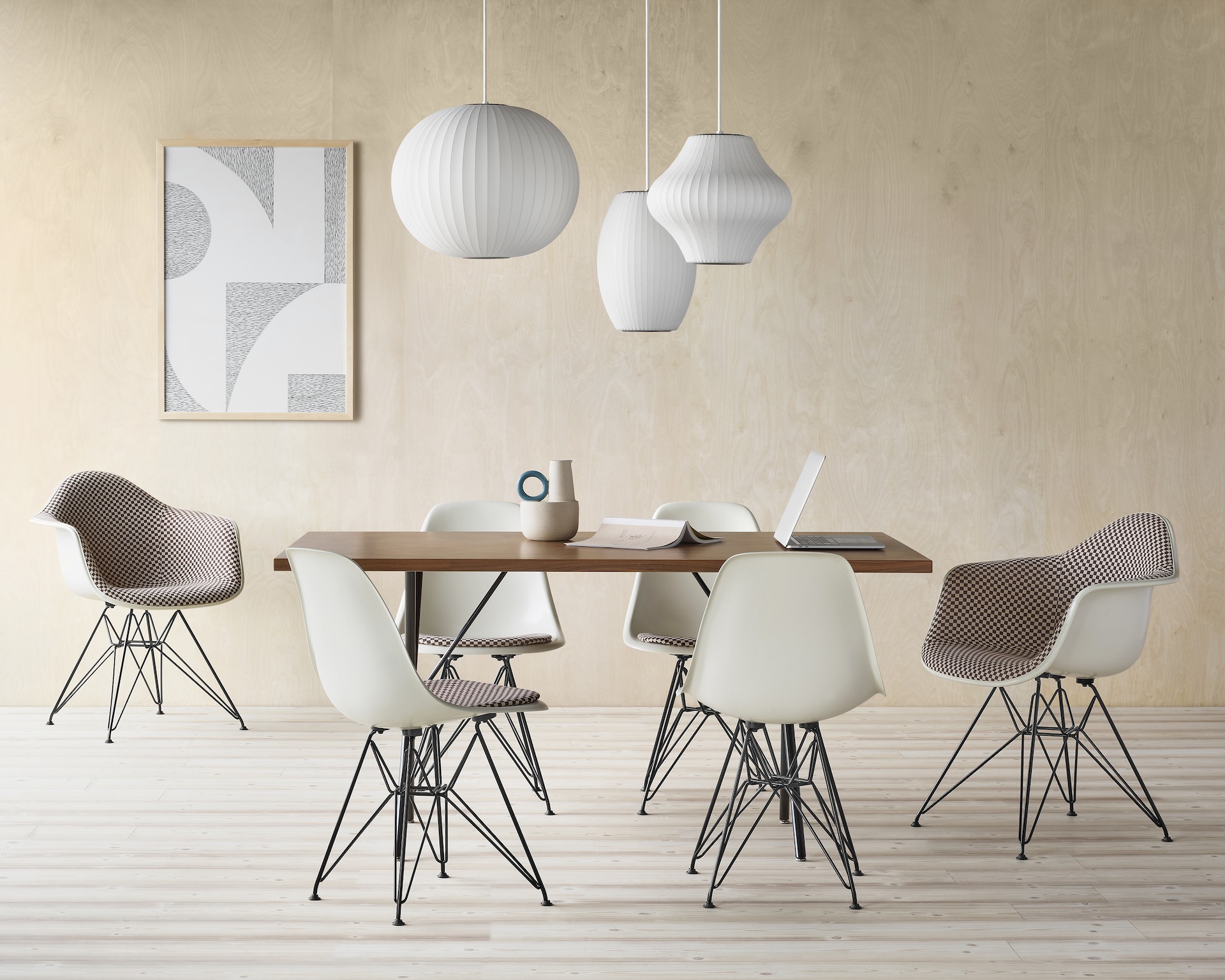 Six Eames Molded Fiberglass Chairs with parchment shells and upholstered seat pads arranged around a Nelson X-leg table in a conference room setting.