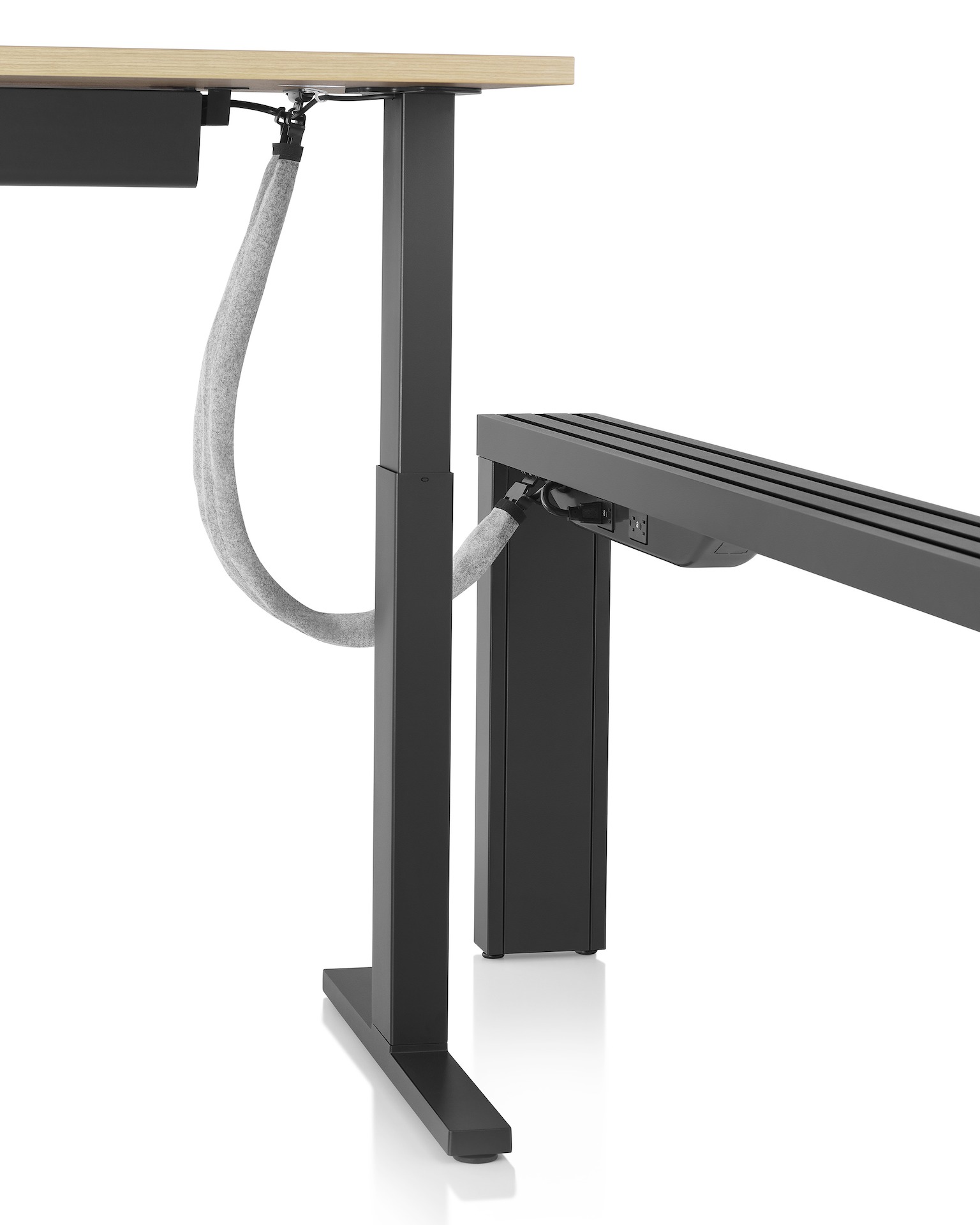 Black Canvas Vista power and data chase connected to a Motia height-adjustable table with cable management trough. 