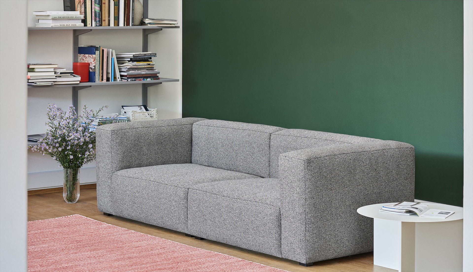 Grey, 2-piece Mags Sectional Sofa with white, round Slit Table in a living room.