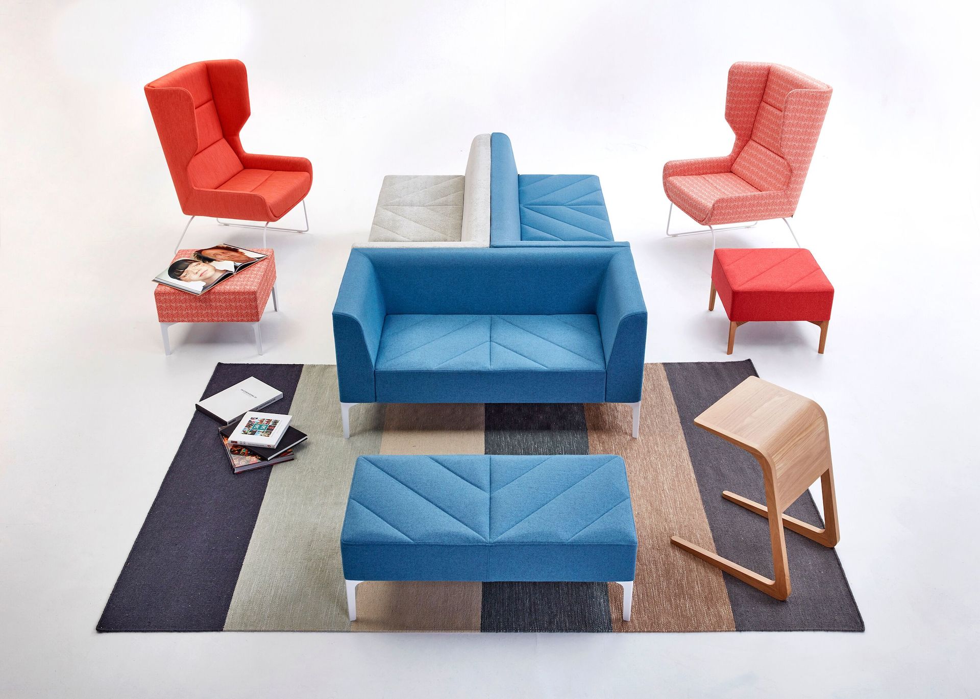 Light blue and gray Hatch Modular Seating, Sofa, and Benches along with two Hush Chairs and an oak Riley Table.