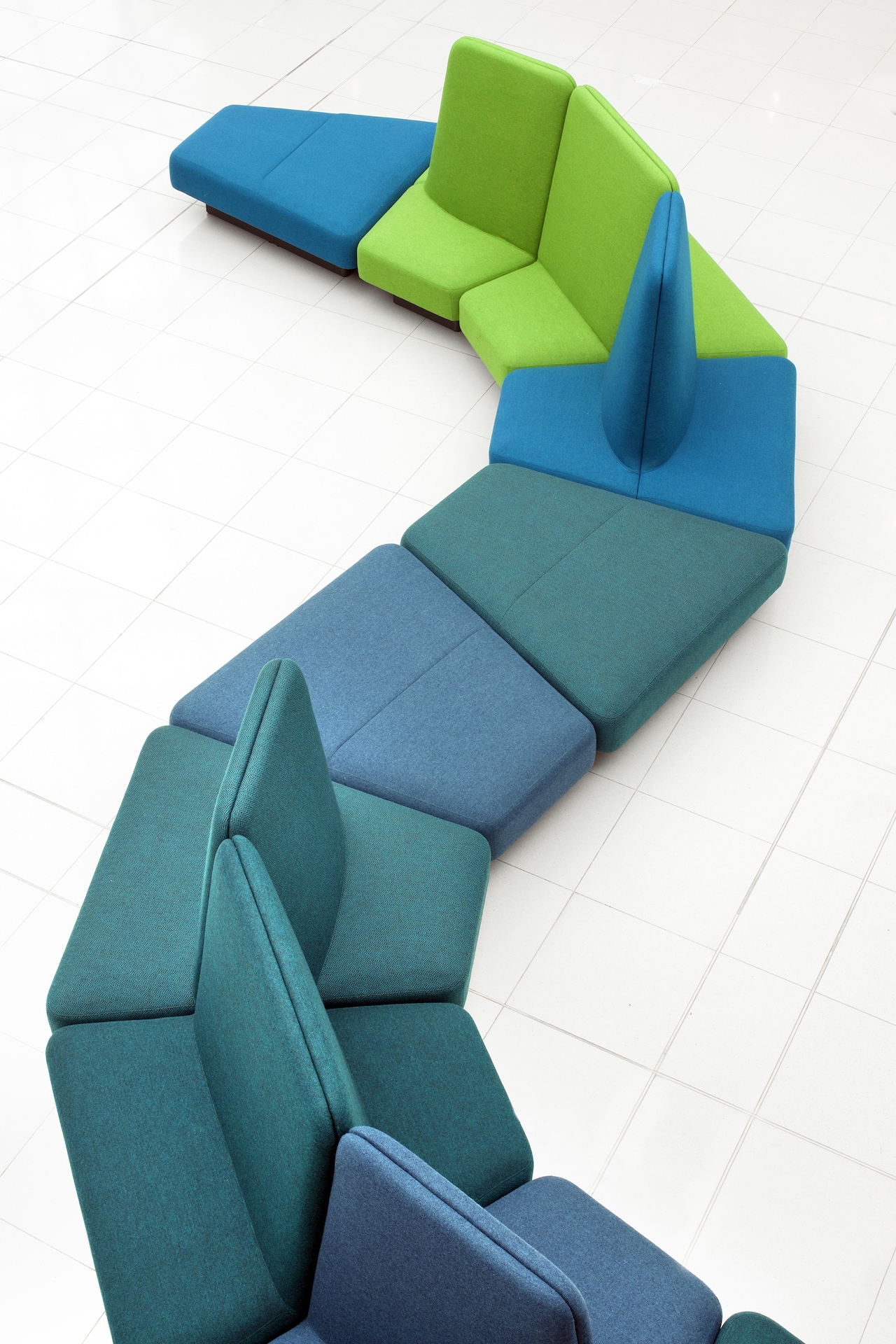 An overhead view of a Rhyme Modular Seating arrangement with shades of blue and green snaking across a white tiled floor.