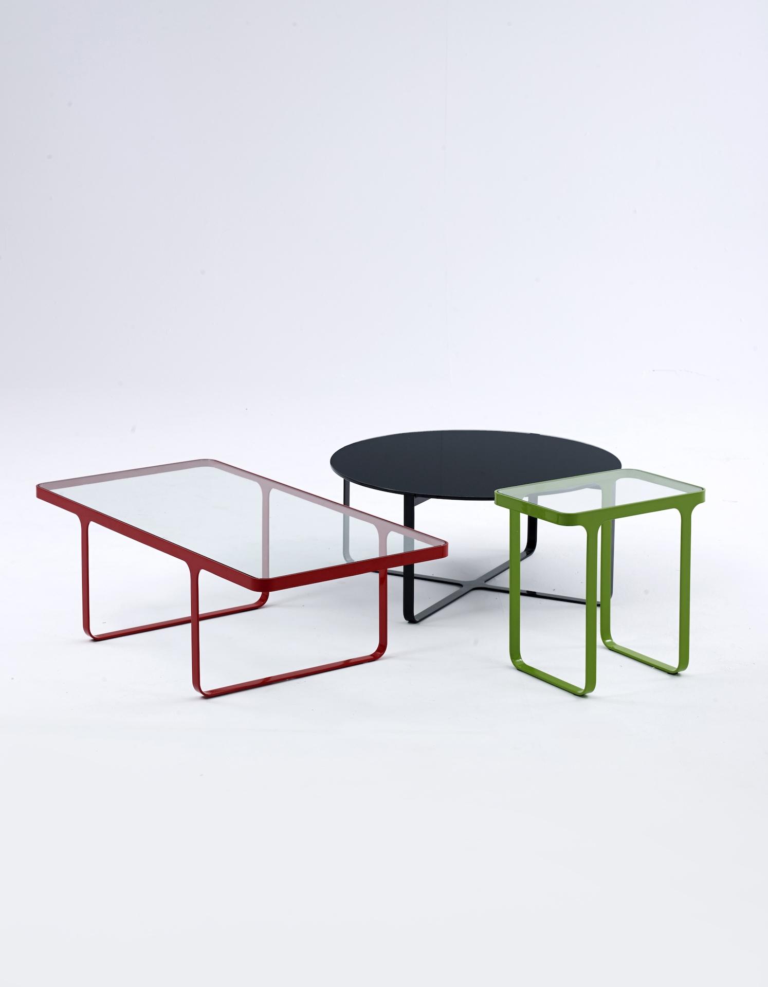 The small naughtone Trace Table family featuring a red Trace Coffee Table, a green Trace Side Table, and an all black round Trace Coffee Table.