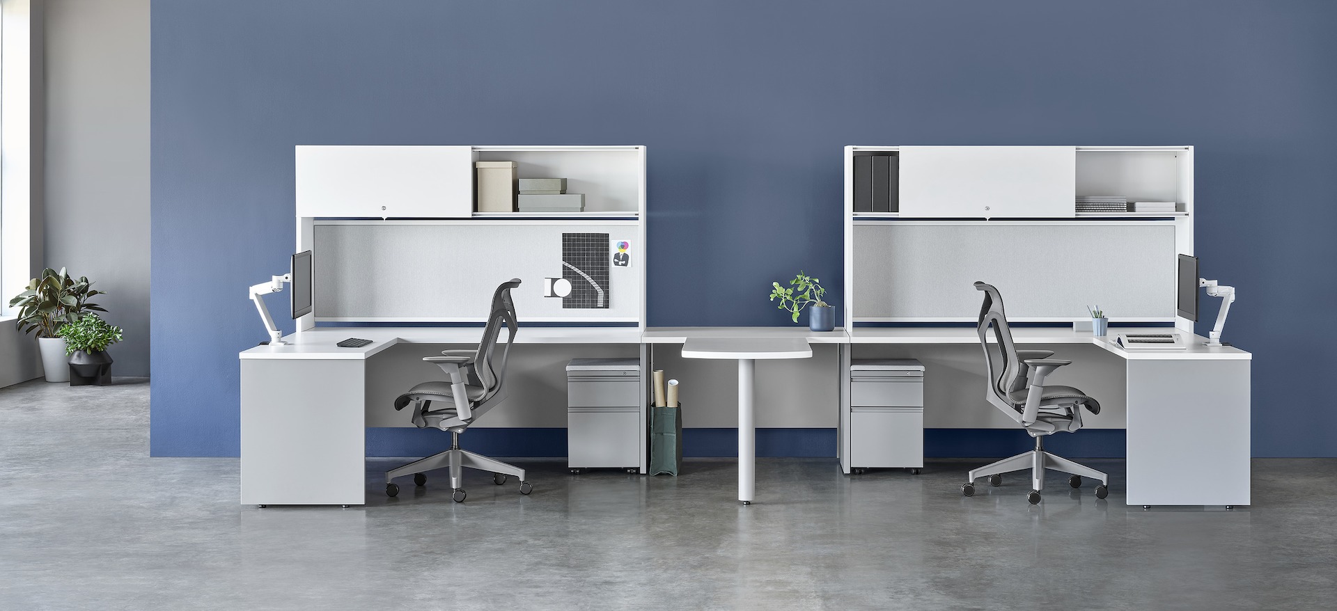 White and gray Canvas Metal Desks with overhead storage, peninsula surface, and gray Cosm Chairs.