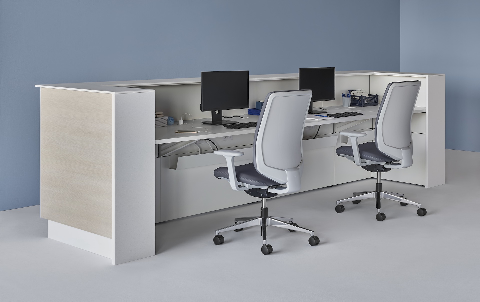 Prefab Commend Nurses Station for two with light woodgrain laminate fronts and white Corian transaction surfaces, Verus Chairs, and monitor stands.