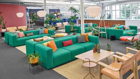Una serie di divani verdi Mags Soft davanti a due sedie in uno spazio collaborativo.