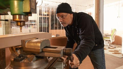 Designer Brian Alexander wearing safety glasses while working on a machine in his studio.