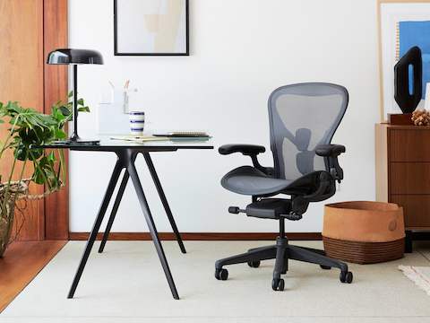 A black Aeron Chair next to a Magis Baguette Table. A black Ode Lamp sits on top of the Magis Baguette Table.