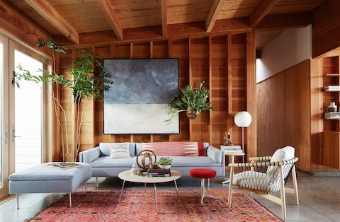 Light  blue Bolster Sofa Group sofa with ottoman, Eames Molded Plywood Coffee Table, red Nelson Pedastal Stool, and Nelson floor lamp in casual setting.