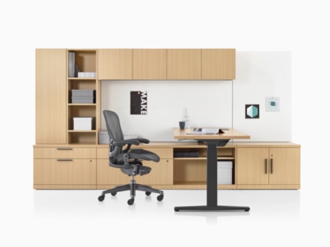 Una oficina Canvas Private Office con almacenamiento de madera clara, un escritorio de altura ajustable, y una silla para oficinas Aeron negra.