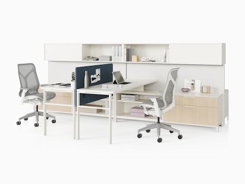 Dos estaciones de trabajo Canvas Wall con almacenamiento de madera clara, superficies blancas, pantallas azules y sillas para oficinas Cosm gris.