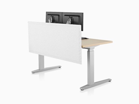 A white privacy screen attached to the back of a sit-to-stand desk supporting two monitors.