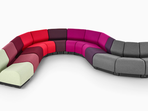 Módulos de sillas modulares Chadwick en gris y varios tonos de rojo y púrpura, en una disposición serpenteante.