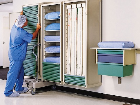 Um profissional de saúde posiciona um armário Co / Struc móvel em um trilho de parede.