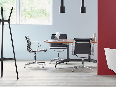 Eames桌子周围配有黑色Eames Aluminum 组合中后座椅的会议室。