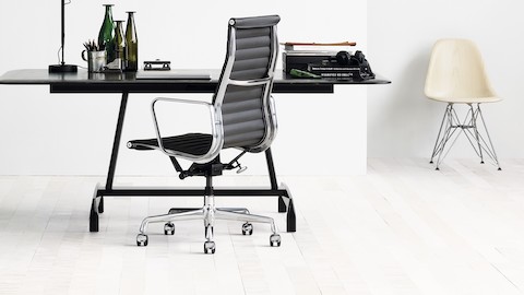 带Eames AluminumGroup黑色椅子，黑色AGL桌子和白色Eames模压玻璃纤维椅子的小办公室。