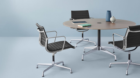 3つの黒Eames Aluminum Groupミッドバックの椅子は、丸いEamesテーブルを囲んでいます。