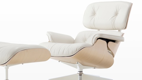 White leather Eames Lounge Chair and Ottoman with a white ash veneer shell, viewed from a 45-degree angle. 