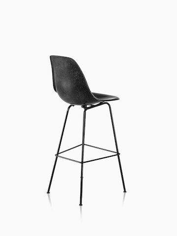 黑色Eames模压玻璃钢凳子的四分之三后视图。