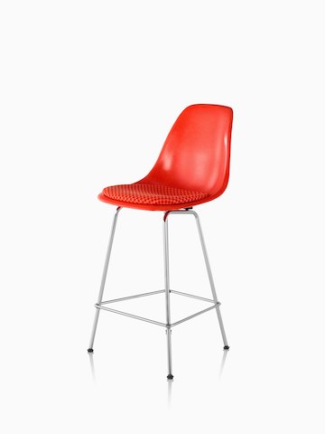 红色Eames模制玻璃钢凳子与45°角的红色座垫。