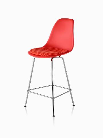 红色Eames塑造塑料凳子与一个红色的座垫，从45度角看。