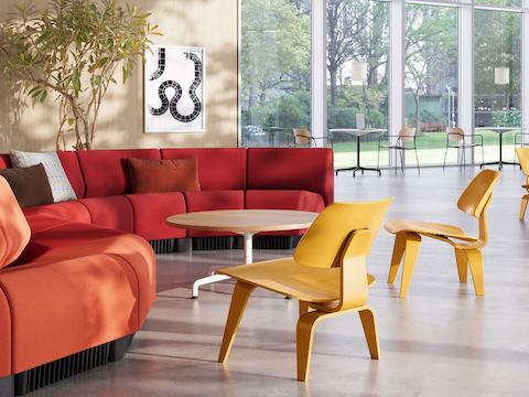 Vestíbulo delantero que incluye el sofá Chadwick y la silla de madera laminada moldeada (LCW) Eames en tinte amarillo.
