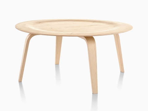 A round Eames Molded Plywood Coffee Table with wood legs and an indented top in a light finish. 