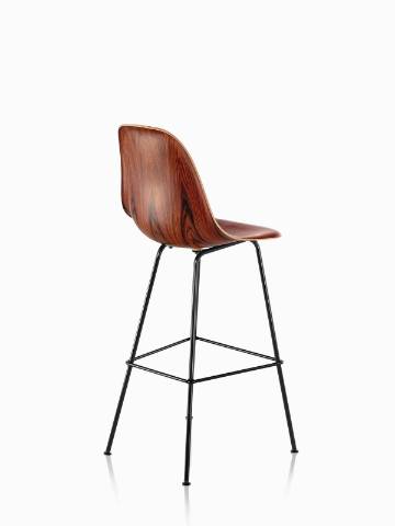 Three-quarter rear view of an Eames Molded Wood Stool with a dark finish and black legs. 