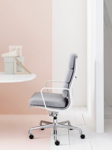 Vista do perfil de Eames Soft Pad cadeira executiva de encosto alto em estofamento cinza claro.