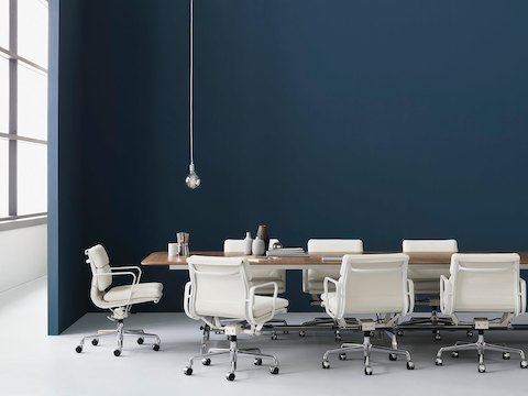 白色皮革Eames Soft Pad椅子围绕一个矩形会议桌。
