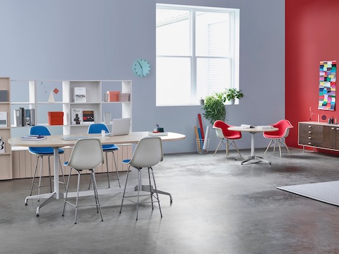 椭圆形和圆形Eames协作区域中的表格还具有Eames模塑塑料扶手椅和凳子，蓝色和红色。