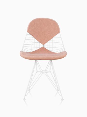 Uma cadeira Eames Wire com assento e encosto tipo bikini, estofada com um tecido rosa claro. Vista de frente.