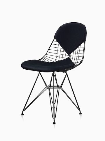 Uma cadeira Eames Wire preta com assento e encosto tipo bikini. A cadeira tem uma base em arame trançado preto. Vista em ângulo.