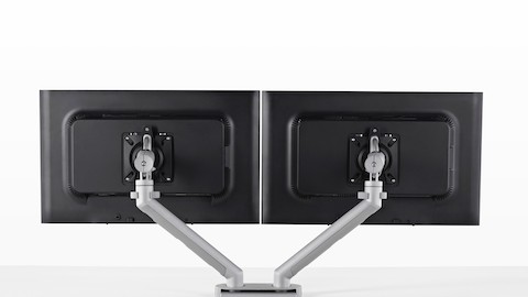 Rear view of side-by-side monitors supported by a Flo Dual Monitor Arm that's attached to a desk.
