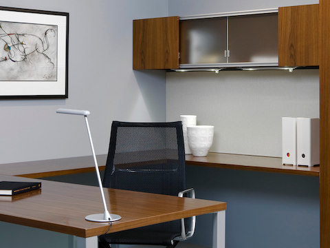 A white freestanding Flute Personal Light perched on the edge of a work surface in a private office.