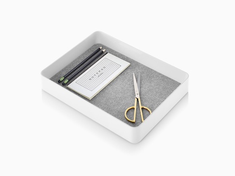 Una papelera corta Formwork blanca con un forro antideslizante con un bloc de notas, tijeras y lápices.