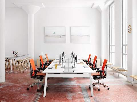 一个明亮的工作环境与橙色Mirra 2办公椅和其他凳子和长凳。
