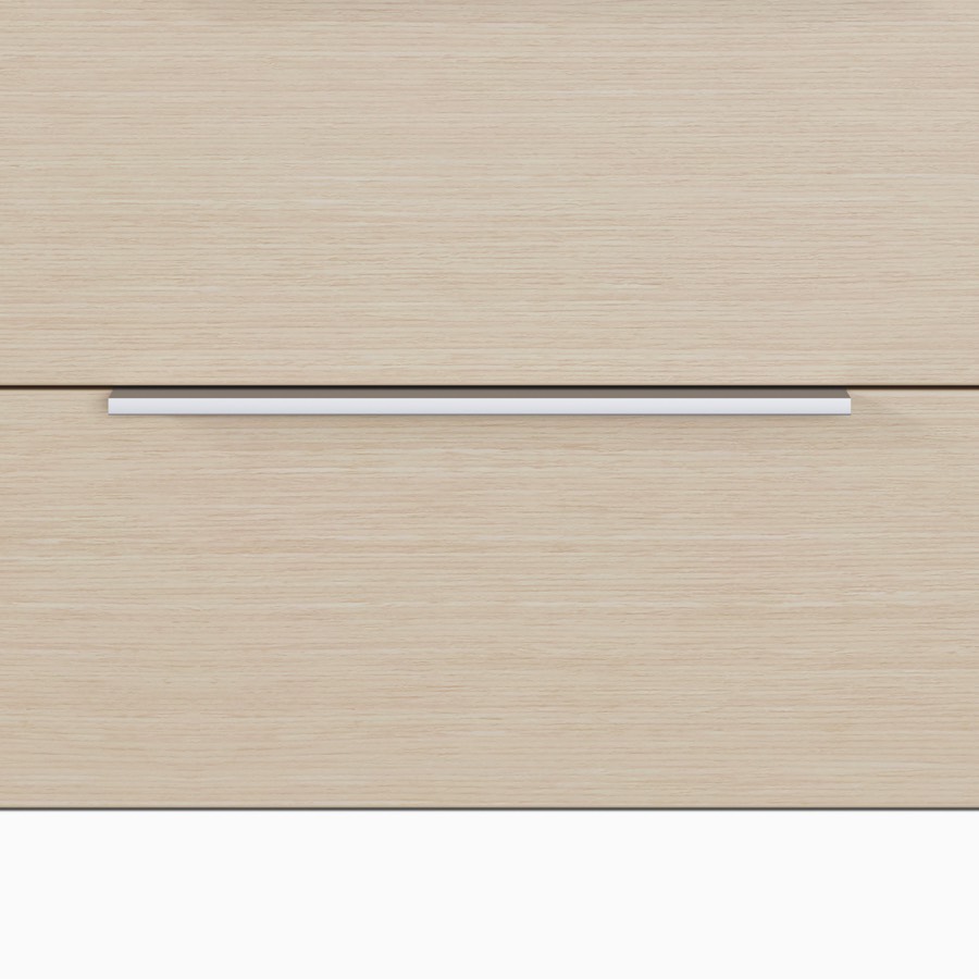 A close-up view of the Mora System casework tab pull in a silver finish on drawers in an ash wood finish.