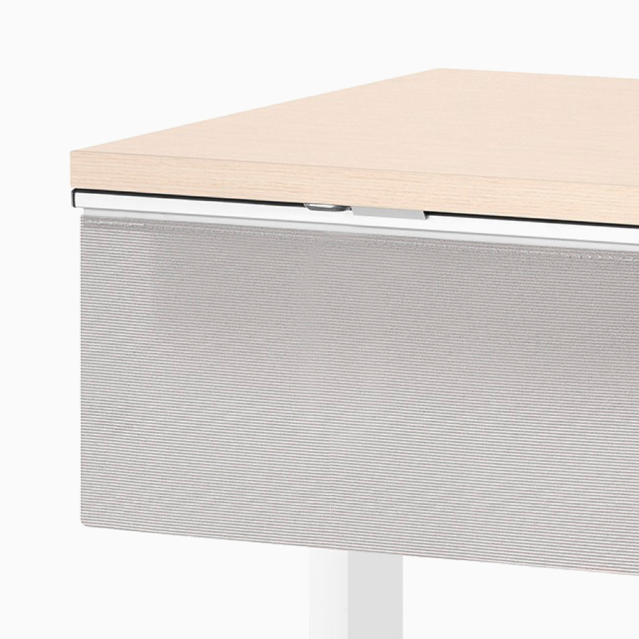 A close-up view of a gray modesty panel attached to the surface of a Nevi standing desk. 