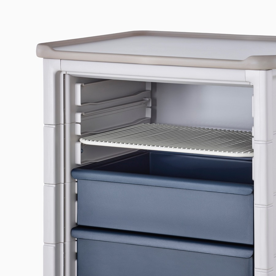 Detail of Procedure and Supply Cart in a light gray body and dark blue modular drawers with a soft white modular wire shelf.