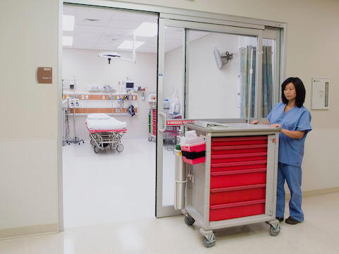 Uma enfermeira empurra um Carrinho de Suprimento / Procedimento móvel com sete gavetas intercambiáveis.