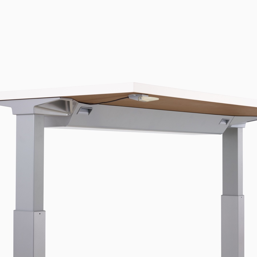 Viewed at an angle, the underside of a Renew sit-to-stand desk with a high-density cable tray and intuitive paddle.