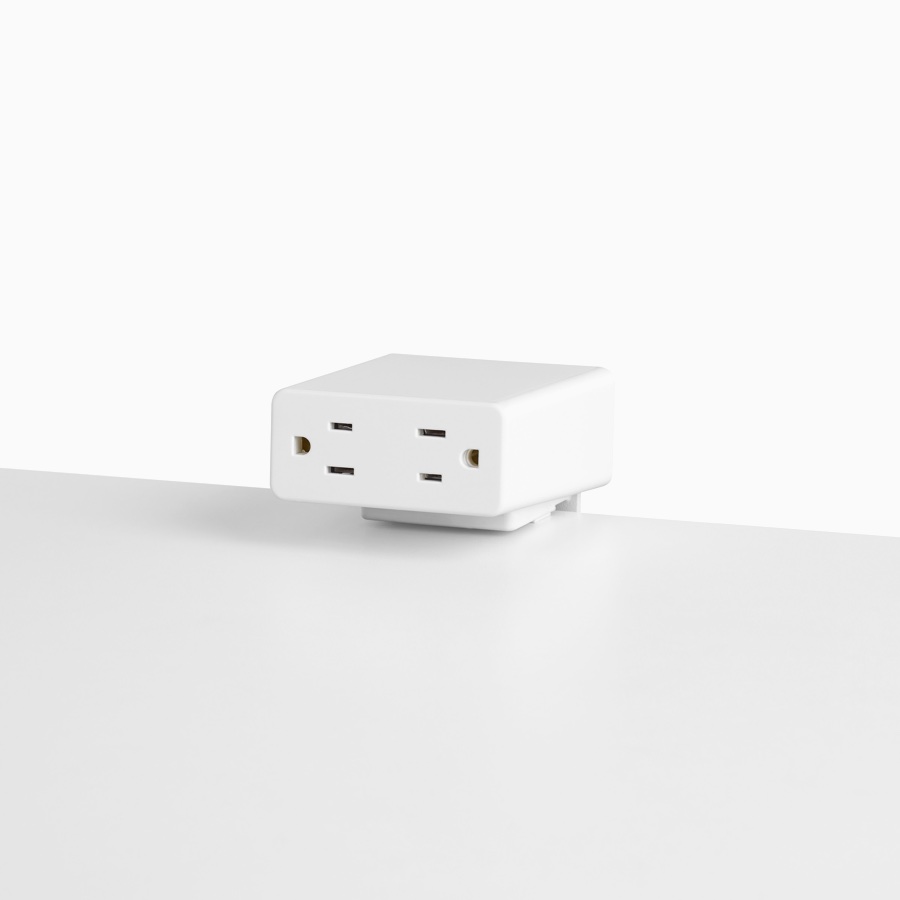 Viewed at an angle, a white Logic Mini with two power outlets, attached to a white work surface.